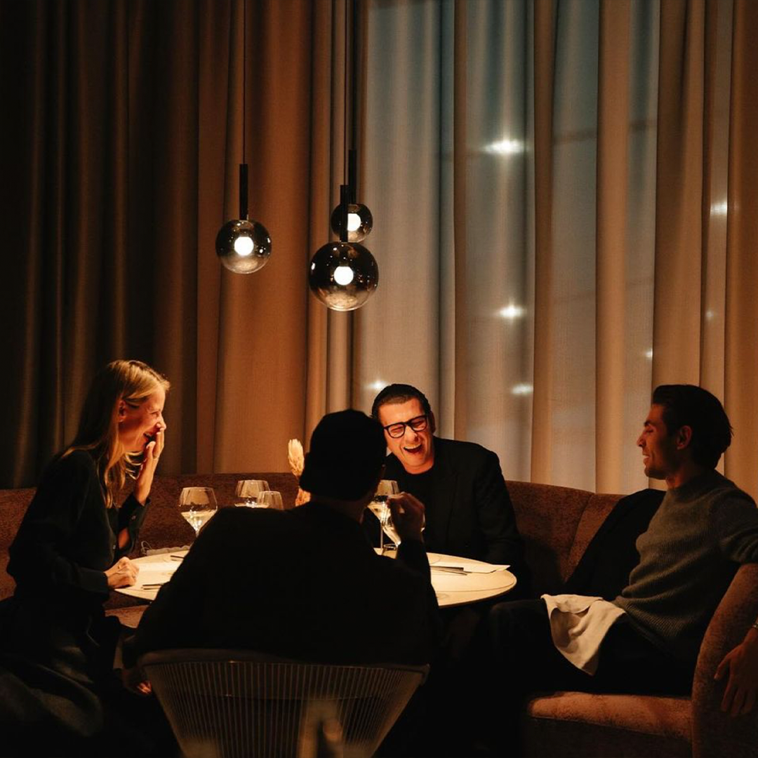 Four people laughing round a restaurant table