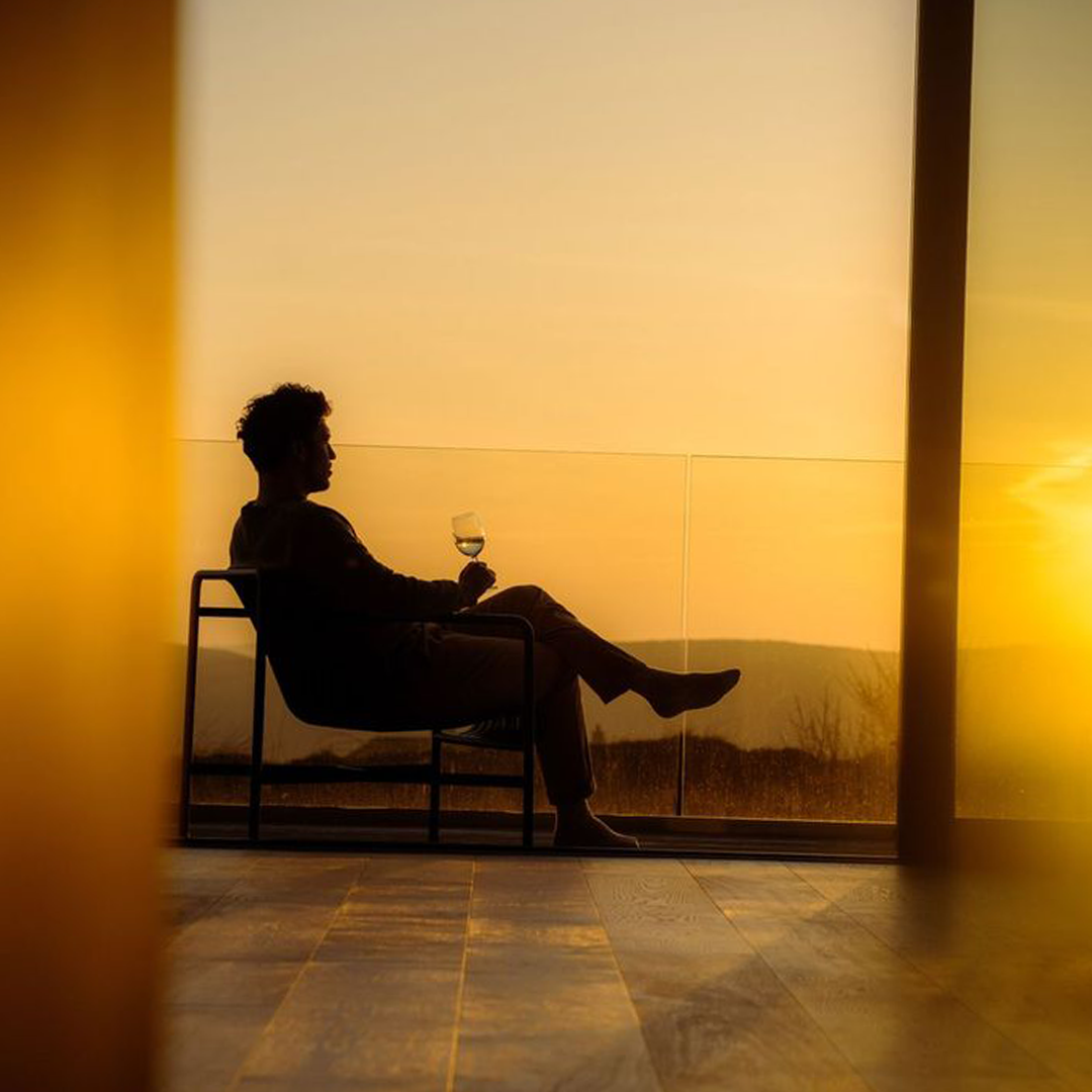 Someone sitting quietly with a drink as the sun goes down