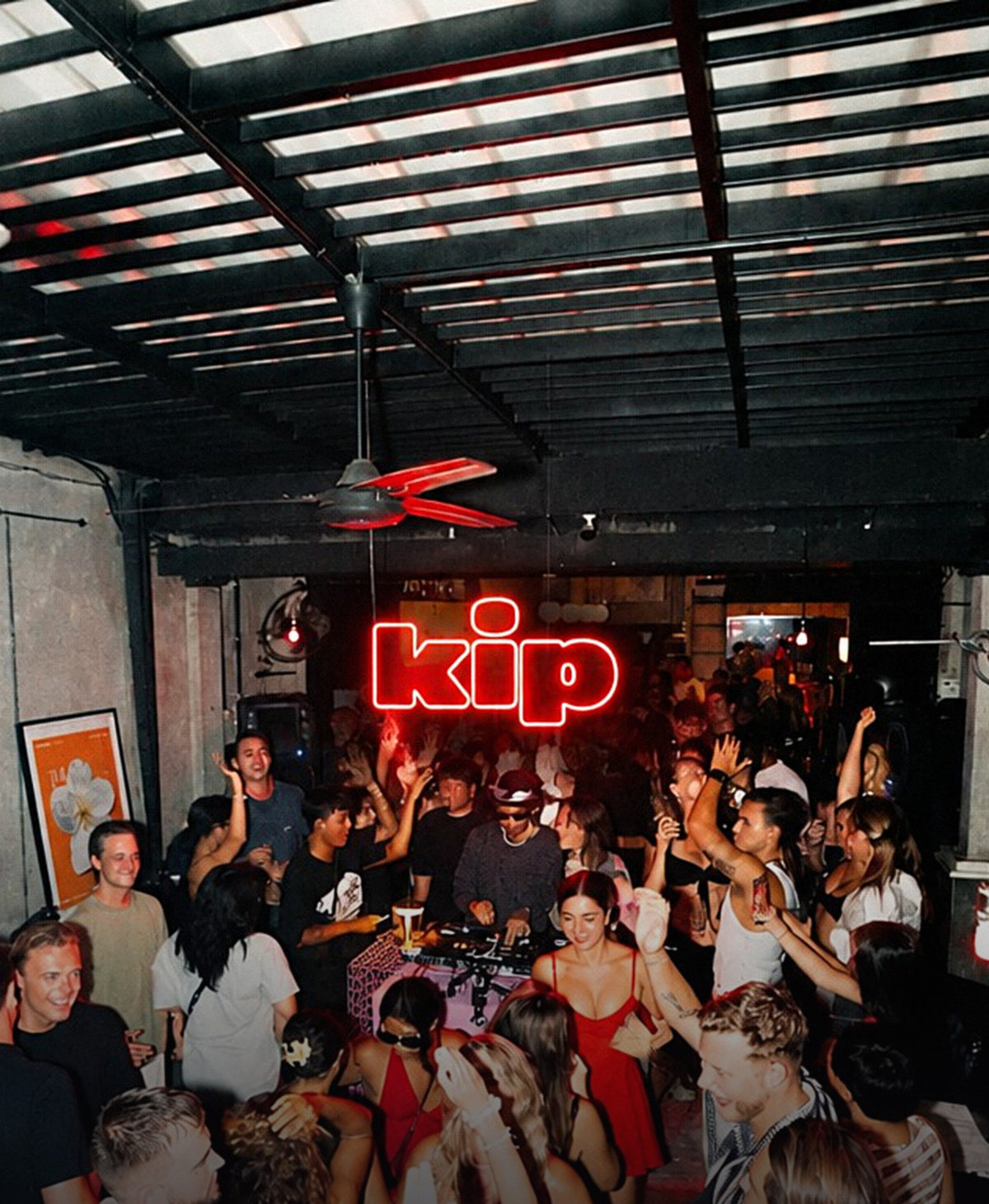 A packed dancefloor under a red neon kip sign