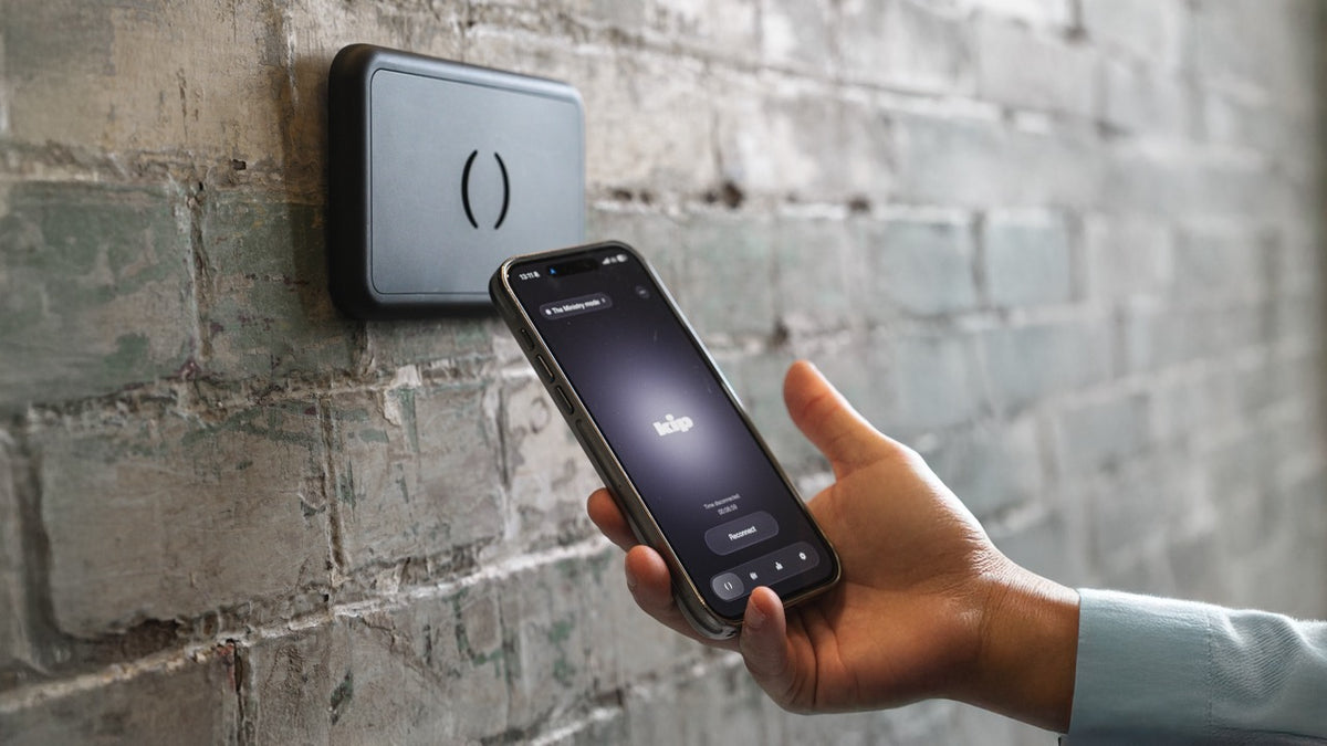 A hand lowers a phone onto the kip smart tag in a venue